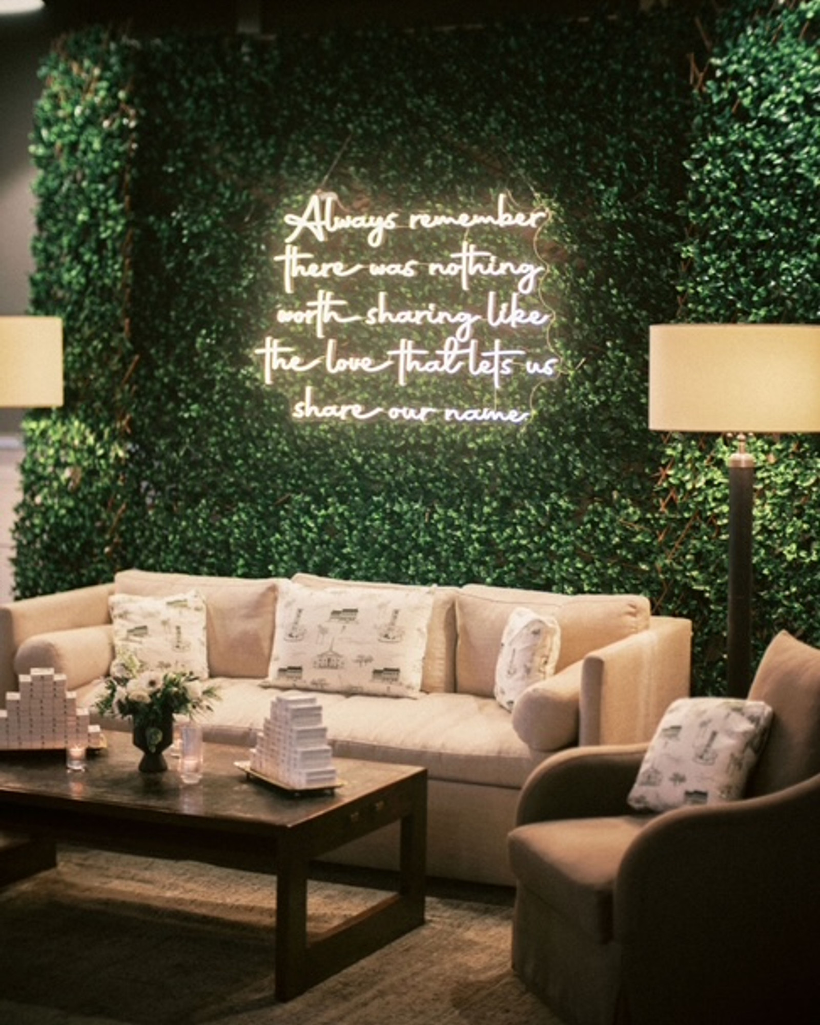 Reception lounge with a custom neon sign and greenery wall